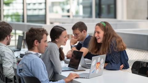 des étudiants en train de discuter devant leur ordinateur. Ils rigolent